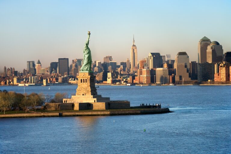 Blick auf die Freiheitsstatue mit der Skyline von New York im Hintergrund.