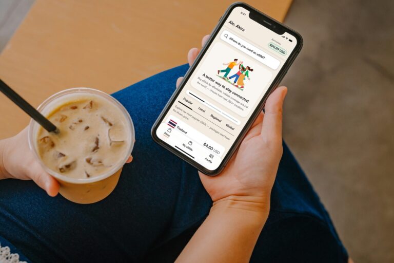 Person genießt Iced Coffee und verwaltet eSIM auf dem Smartphone.